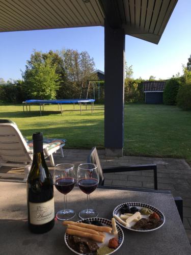 a bottle of wine and glasses on a table with food at Hasmark beach, nice house close to the beach. in Otterup