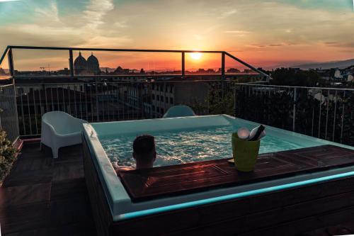 a person sitting in a jacuzzi tub on top of a balcony at Forte16 View & SPA in Florence