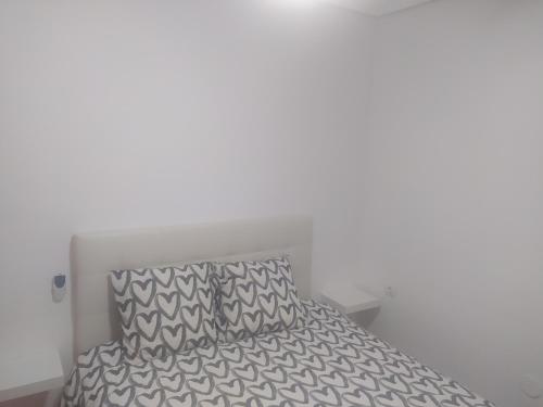 ein Bett mit einer grauen und weißen Bettdecke und einem Kissen in der Unterkunft APARTAMENTO Daniel in Benalmádena