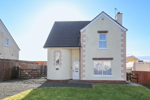 a white house with a fence in a yard at The Ferns-Ideal base for exploring the Causeway Coast in Armoy