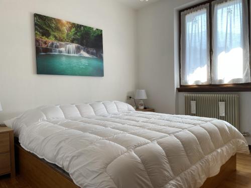 a large white bed in a bedroom with a painting on the wall at 072 Trilocale, Giustino in Giustino
