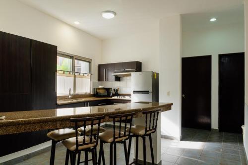 a kitchen with a bar with stools at a counter at Almarea Vacation Condo in Playa del Carmen