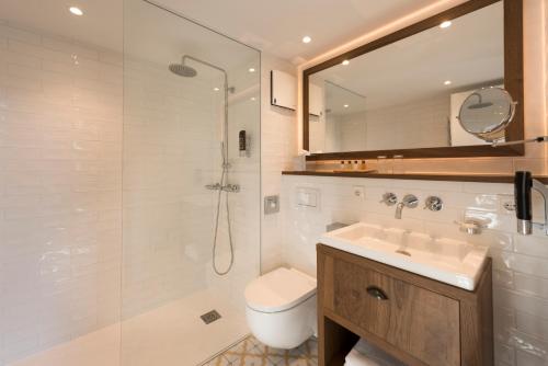a bathroom with a shower and a sink and a toilet at LOEV - VELA Hotels in Binz