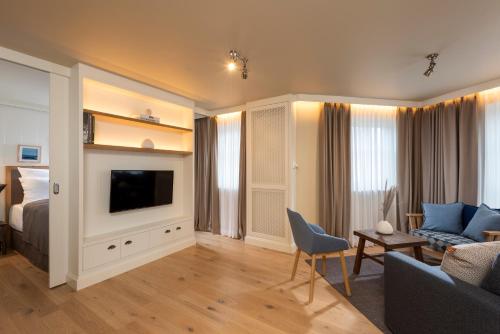 a living room with a couch and a tv and a bed at LOEV - VELA Hotels in Binz