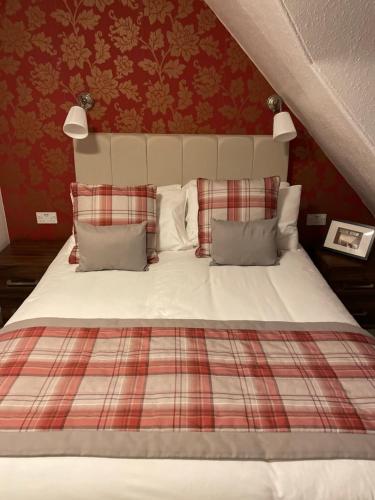 Cama con manta a cuadros y almohadas en Royston Guest House Inverness, en Inverness