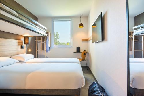 um quarto de hotel com três camas e uma janela em Ibis Budget Paris porte de la Chapelle - Aréna em Paris
