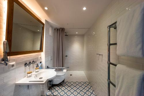 a white bathroom with a sink and a mirror at LOEV - VELA Hotels in Binz