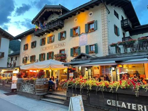 ein Hotel mit Leuten, die vor dem Hotel an Tischen sitzen in der Unterkunft Hotel Alpina in Livigno