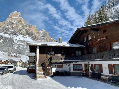 a ski lodge with a snow covered mountain in the background at Garni La Vara in Corvara in Badia