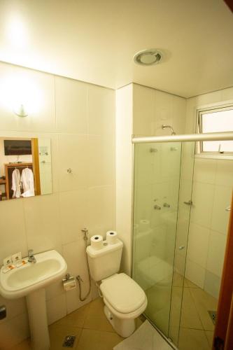 a bathroom with a toilet and a sink and a shower at Carlton Plaza Torre in Araxá