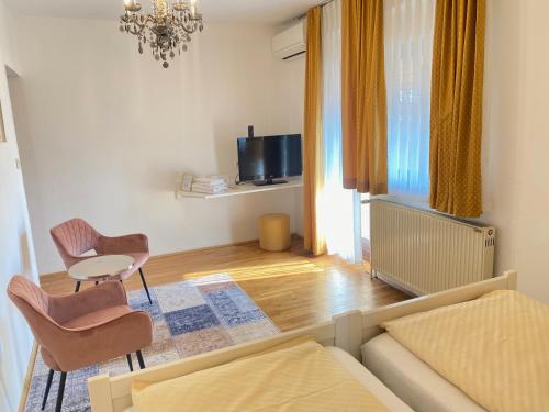 a living room with a couch and chairs and a tv at Kunstelj Pension in Radovljica