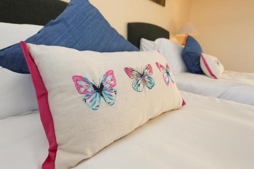 a pillow with butterflies on it sitting on a bed at The Ferns-Ideal base for exploring the Causeway Coast in Armoy