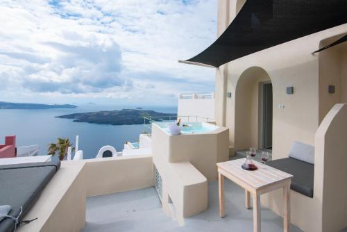 a balcony with a table and a view of the water at Caldera Cliff Illusion in Fira