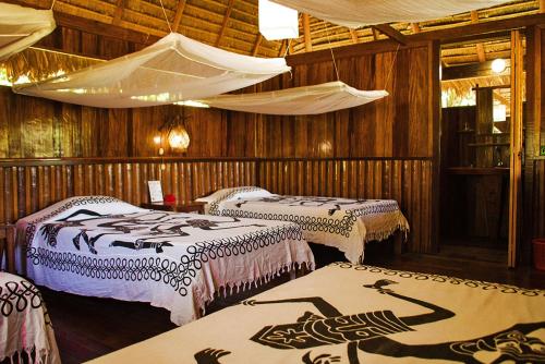 Habitación con 3 camas y paredes de madera. en Corto Maltes Amazonia Lodge, en Puerto Maldonado