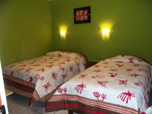 two beds in a room with green walls at Hostal Boulevard in Nazca