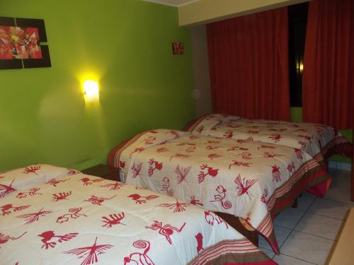 two beds in a room with green walls at Hostal Boulevard in Nazca