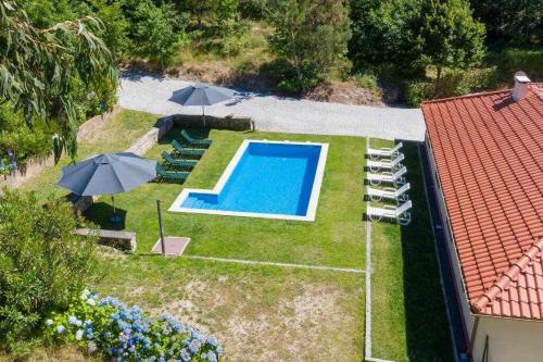 eine Luftansicht auf einen Hinterhof mit Pool und Sonnenschirmen in der Unterkunft Casa do Pioledo Camélias de Basto in Lamelas