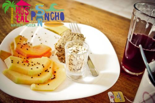 a plate of food with fruit and a glass of water at Hostal San Pancho in San Francisco
