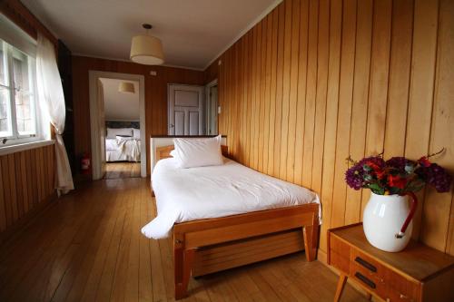 a bedroom with a bed with a vase of flowers at Hotel Boutique Casa Werner in Puerto Varas