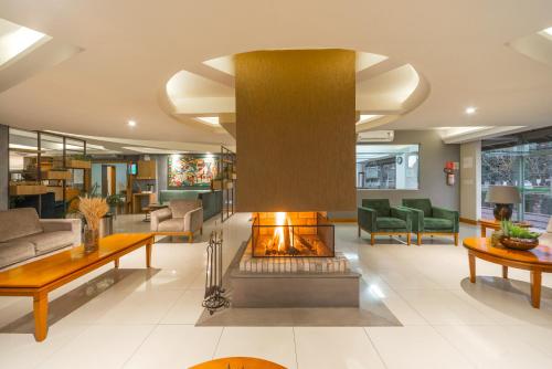 a living room with a fireplace in the middle at Hotel Laghetto Premio in Gramado