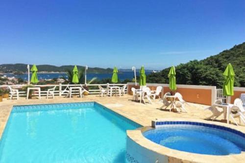 a swimming pool with chairs and umbrellas at Porto Almar Búzios in Búzios