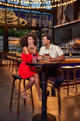 a man and woman sitting at a table in a bar at The Rally Hotel at McGregor Square in Denver