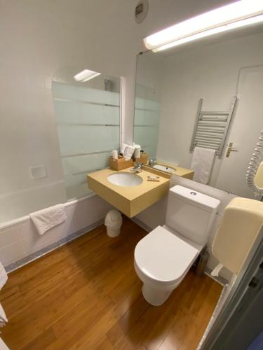 W łazience znajduje się toaleta, umywalka i lustro. w obiekcie Savoie Hotel aux portes de Genève w mieście Saint-Julien-en-Genevois