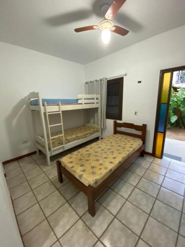 a bedroom with two bunk beds and a ceiling fan at Chalés Mariah in Ubatuba