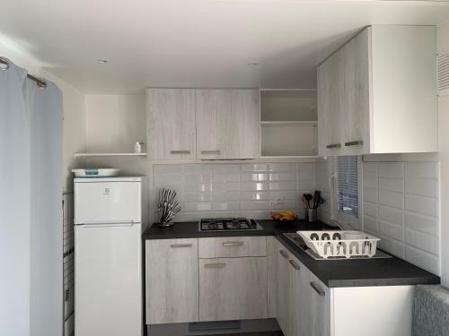 a kitchen with white cabinets and a white refrigerator at Torre Mendari in Varigotti