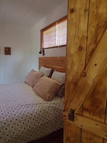 - une chambre avec un lit et une porte en bois dans l'établissement La Maison du Potager, à Saint-Racho