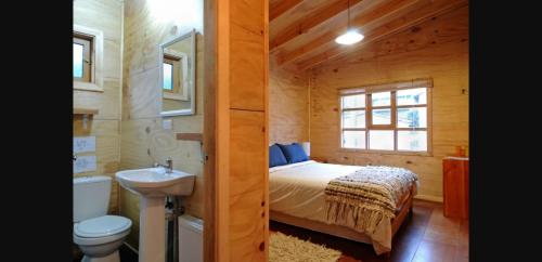 a bedroom with a bed and a sink and a toilet at Hostal Palafito Waiwen in Castro