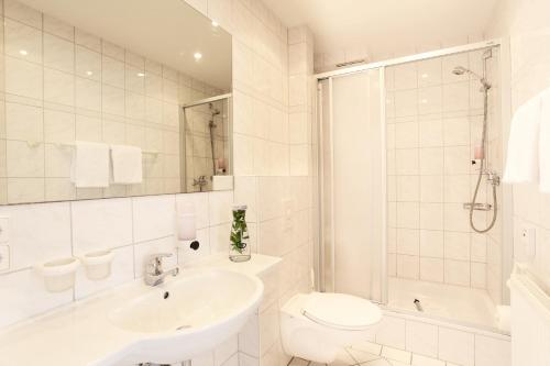 a white bathroom with a sink and a toilet at Hotel Wulff in Bad Sassendorf