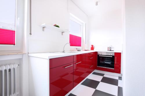 a kitchen with red cabinets and a black and white floor at Hotel Wulff in Bad Sassendorf