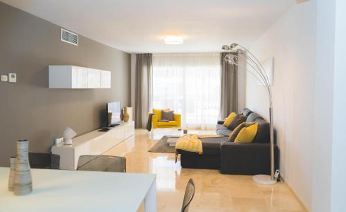 een woonkamer met een zwarte bank en gele kussens bij Moderno Apartamento en Guadalmina Golf - Marbella in Marbella