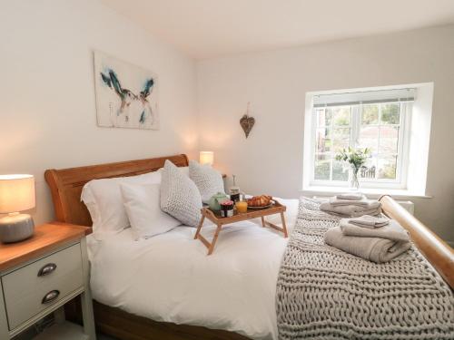 Schlafzimmer mit einem Bett mit einem Tisch und einem Fenster in der Unterkunft Jasmine Cottage in Axminster