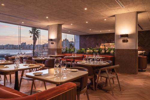 a restaurant with tables and chairs and a view of the city at Costanero Hotel Montevideo - MGallery Collection in Montevideo