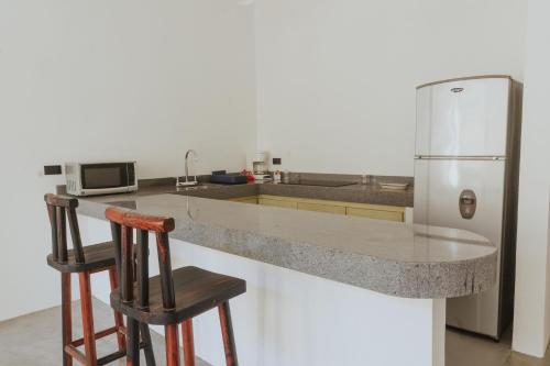 a kitchen with a refrigerator and two bar stools at Villas Colón 18 in Coatepec