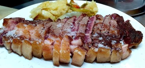 a piece of meat and potatoes on a white plate at Hostal Restaurante Serrania in Tragacete