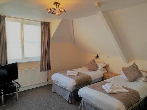 a hotel room with two beds and a television at Membly Hall Hotel in Falmouth