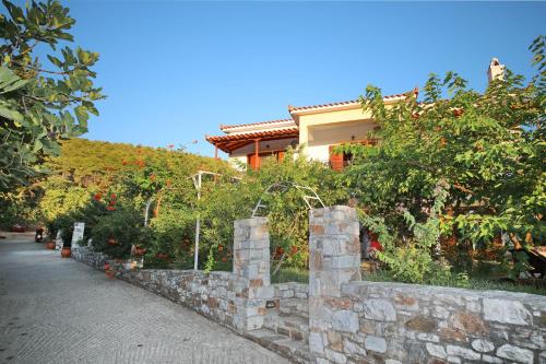 a house on a hill next to a stone wall at Koromilia Villa in Neo Klima