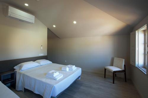 a bedroom with a bed and a chair and a window at Rua Grande Hotel in Viana do Castelo
