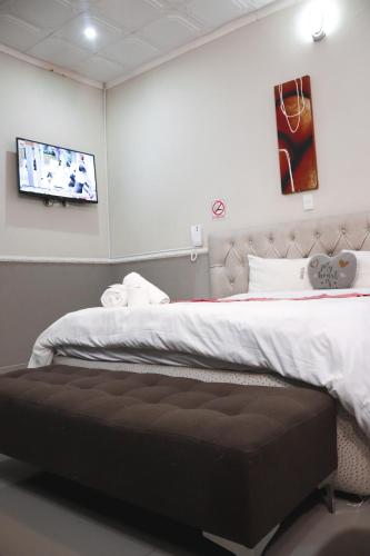 a bedroom with a bed and a tv on the wall at Gold Crown International Hotel With Complementary Breakfast and WiFi in Johannesburg