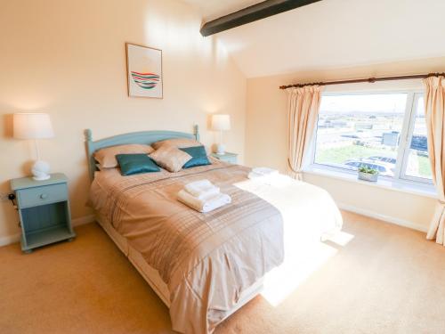 a bedroom with a bed and a large window at Malltraeth Cottage in Bodorgan