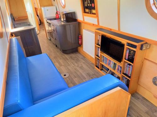 a living room with a blue couch and a tv at Smoke (Rowington Narrowboats) in Warwick