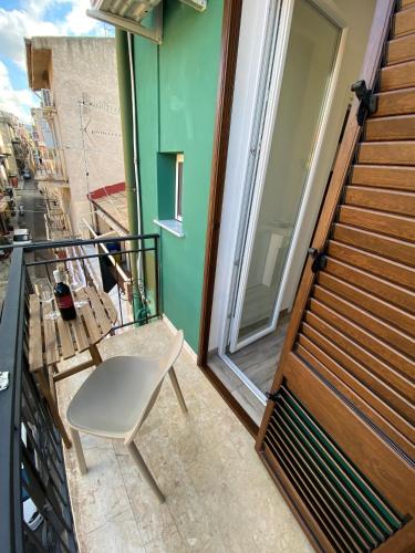 a white chair sitting on a balcony with a window at IN CENTRO ROOMS Vicino Cefalù SELF-CHEK-IN in Campofelice di Roccella
