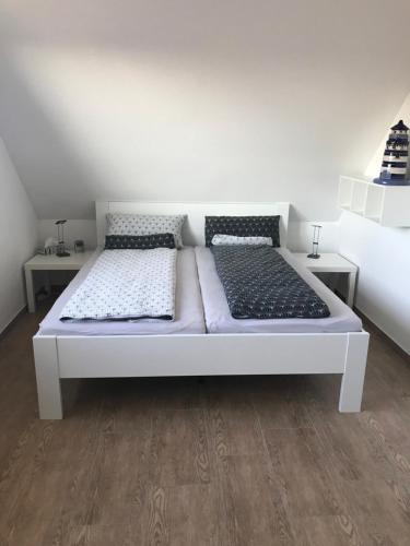 een wit bed met 2 kussens in een kamer bij Haus Margarete Dornum mit Wallbox in Dornum