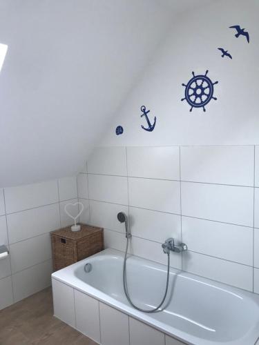 La salle de bains est pourvue d'une baignoire avec une vignette nautique sur le mur. dans l'établissement Feriendomizil Dornum Haus Margarete mit Wallbox, à Dornum