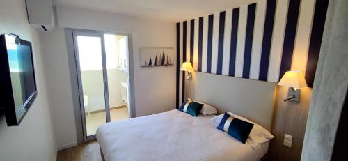 um quarto de hotel com uma cama e uma grande janela em Belle Vue Mer Canet Plage accès piscine couverte et chauffée em Canet-en-Roussillon