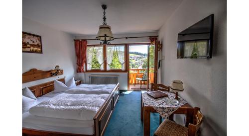 1 dormitorio con cama, mesa y ventana en Hotel Rita, en Schonach