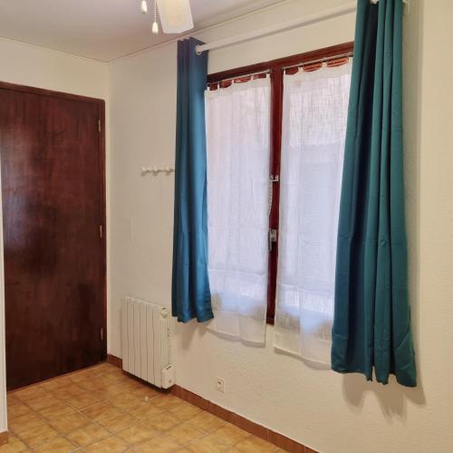 Cette chambre dispose de rideaux bleus et d'une porte. dans l'établissement Studio Cosy près du Lac, à Sainte-Croix-de-Verdon